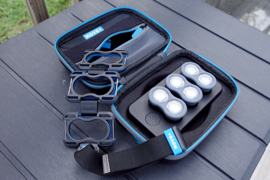 Kineon Move+ charging case open on a table showing three modules, straps, and storage compartments