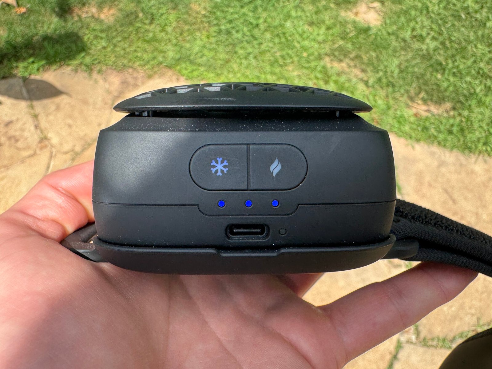Close-up of the Therabody RecoveryTherm Cube control panel showing the dual-button interface with snowflake and flame icons, three illuminated blue LED battery dots, and USB-C charging port below.
